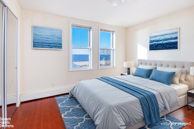 bedroom featuring baseboard heating, a closet, and dark hardwood / wood-style floors