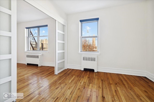 unfurnished room with radiator, built in features, and light hardwood / wood-style floors