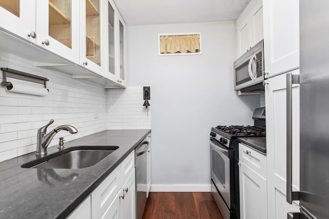 kitchen with white cabinets, decorative backsplash, dark wood-type flooring, stainless steel appliances, and a sink