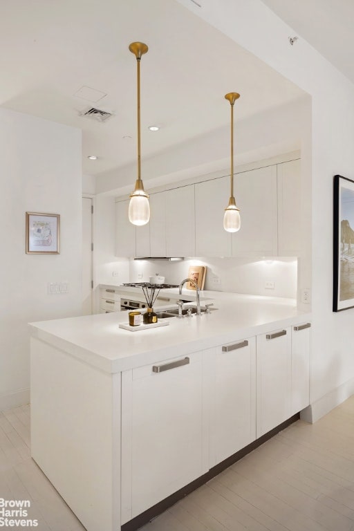 bar featuring hanging light fixtures, sink, and white cabinetry