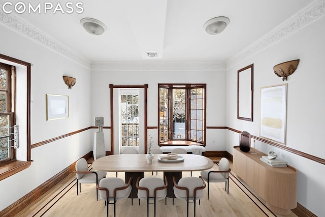 dining space with light hardwood / wood-style flooring and ornamental molding