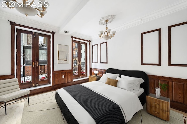 bedroom featuring a chandelier, crown molding, light hardwood / wood-style floors, and french doors