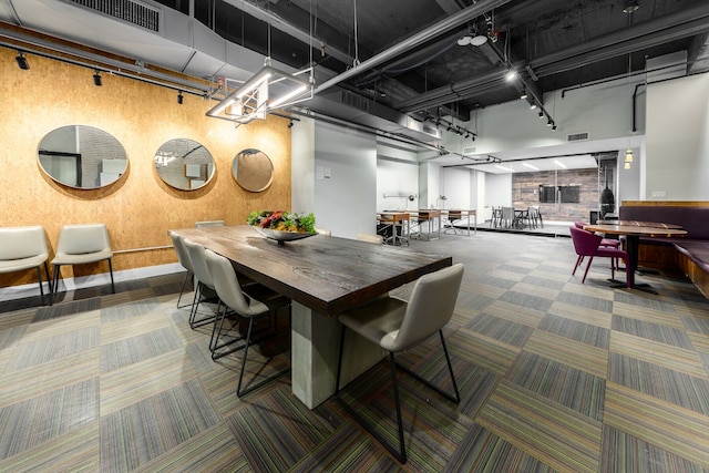 dining room featuring track lighting, a towering ceiling, visible vents, and carpet floors