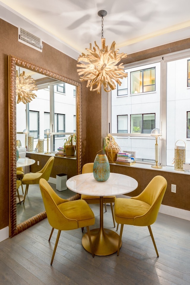 dining room with a notable chandelier, visible vents, baseboards, and hardwood / wood-style floors