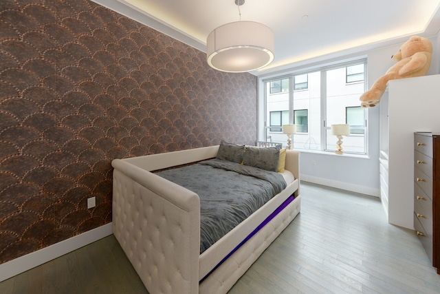 bedroom with wallpapered walls, baseboards, and wood finished floors