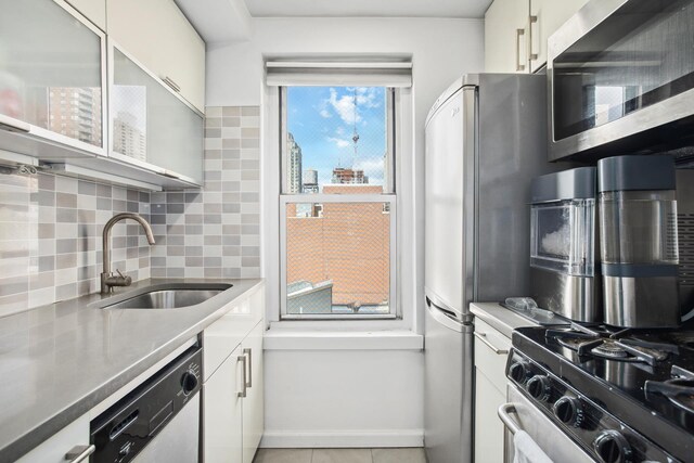 kitchen with tasteful backsplash, white cabinets, sink, and stainless steel appliances