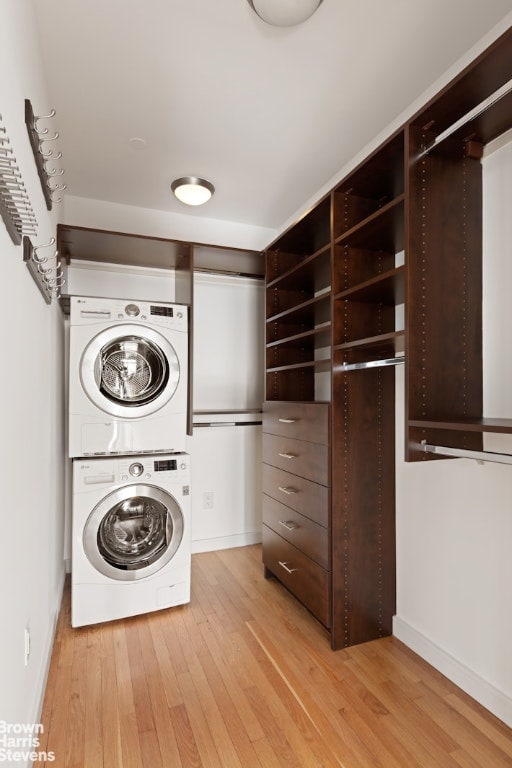 clothes washing area featuring light hardwood / wood-style floors and stacked washing maching and dryer