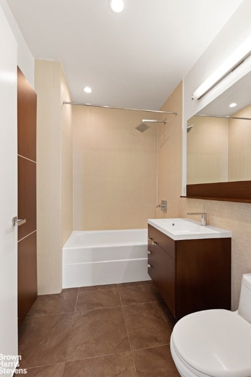 full bathroom with toilet, vanity, tile patterned flooring, tile walls, and tiled shower / bath combo