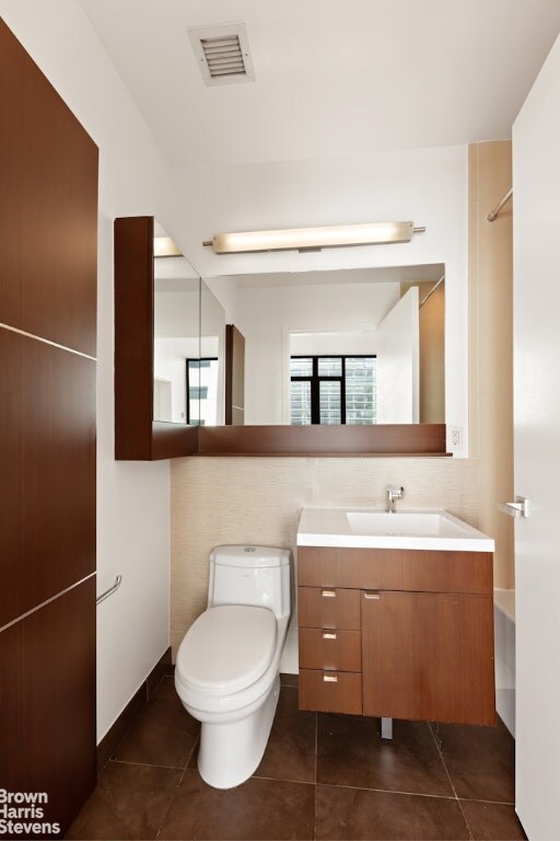 bathroom with toilet, vanity, tile patterned flooring, backsplash, and a bath