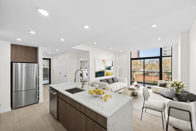 229 Withers St Unit 2B, New York City, NY 11211 - kitchen featuring appliances with stainless steel finishes, open floor plan, light wood-type flooring, expansive windows, and a kitchen island with sink