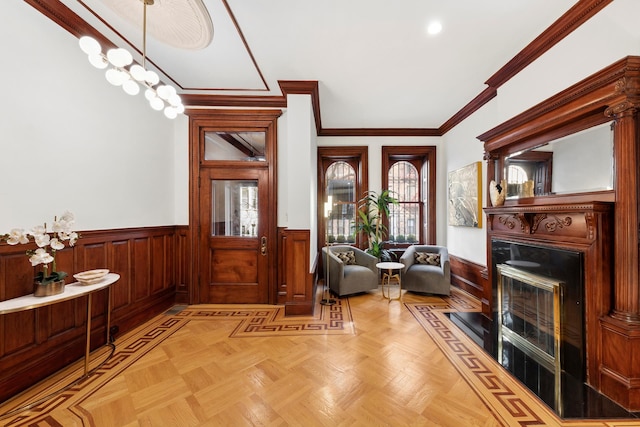 entrance foyer featuring a wainscoted wall, a fireplace, and crown molding