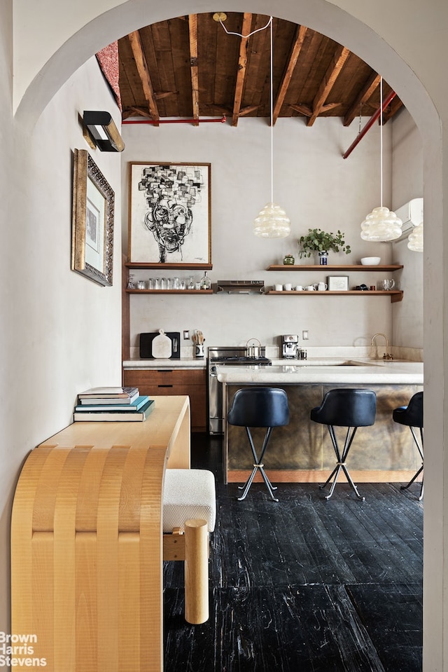 bar featuring beamed ceiling, indoor wet bar, stainless steel range with electric cooktop, arched walkways, and dark wood-style flooring