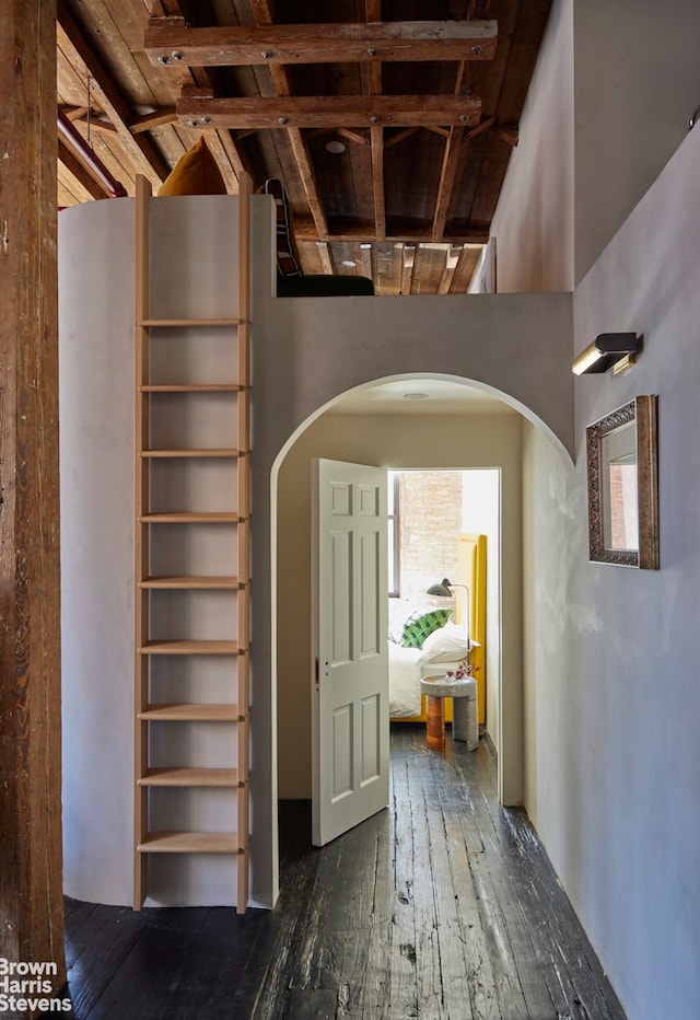 hall featuring dark wood-style floors, arched walkways, and a wealth of natural light