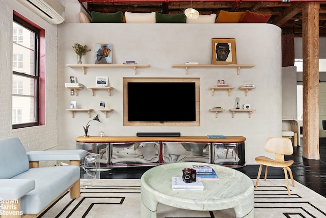 living area featuring wood finished floors, brick wall, and a wall mounted AC