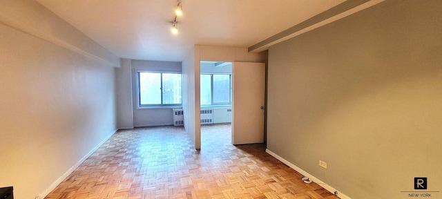 spare room featuring radiator heating unit and light parquet floors