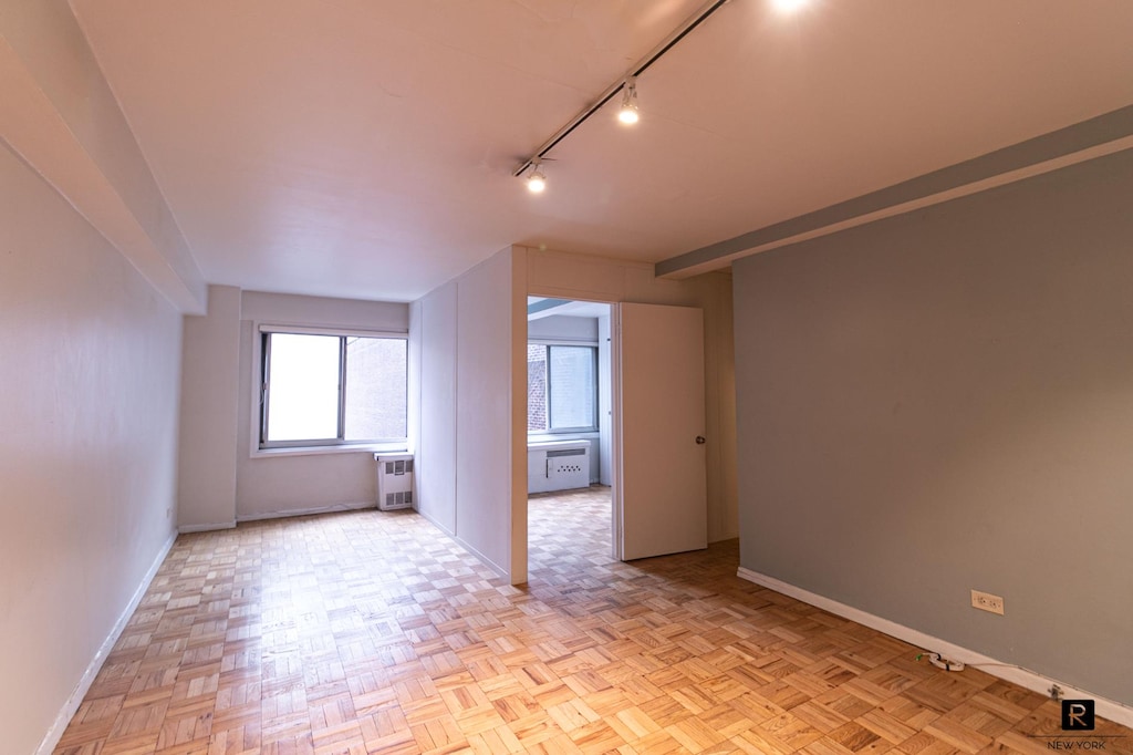 240 E 55th St Unit 9-C, New York City, NY 10022 - empty room with baseboards, track lighting, and heating unit