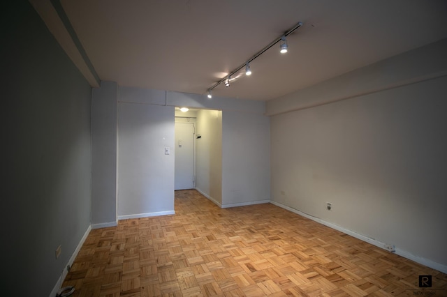 spare room featuring rail lighting and baseboards