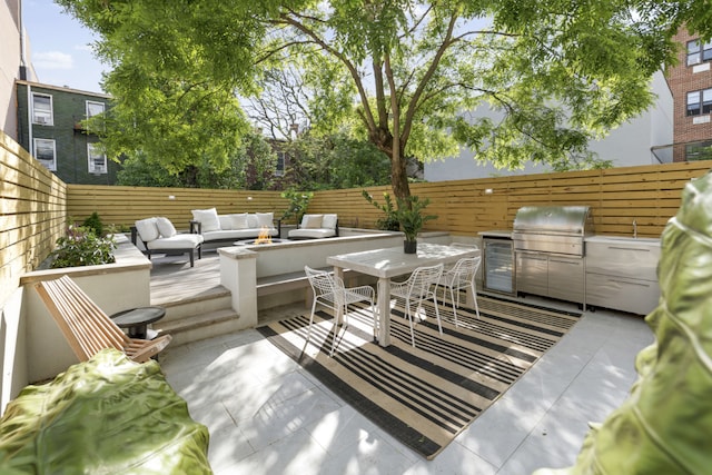 view of patio featuring exterior kitchen, area for grilling, and an outdoor living space with a fire pit