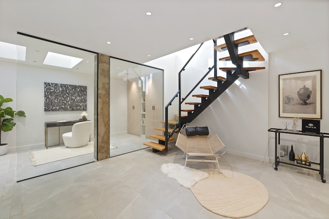 interior space with a skylight, baseboards, stairway, and recessed lighting