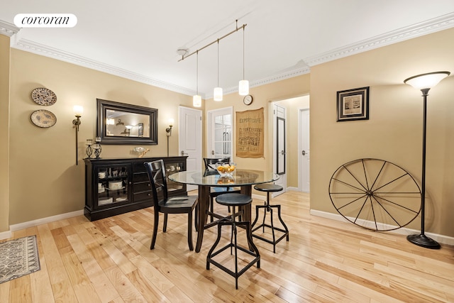 dining room with light wood-style floors, visible vents, crown molding, and baseboards