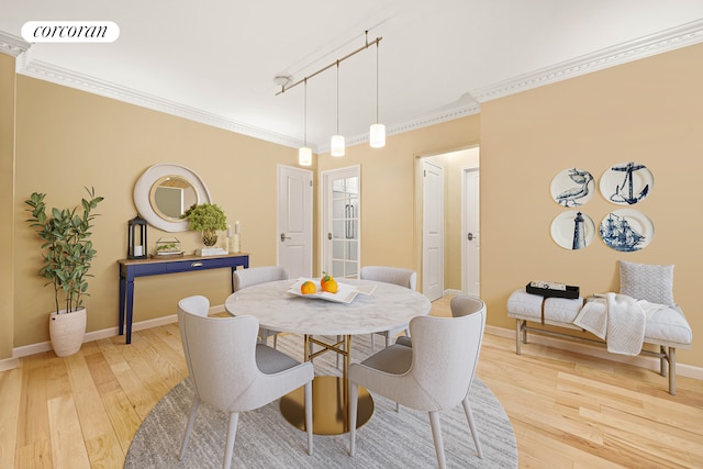 dining space featuring light wood-style floors, baseboards, and crown molding