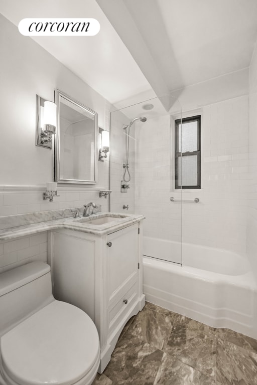 full bathroom with tiled shower / bath, vanity, toilet, and tile walls