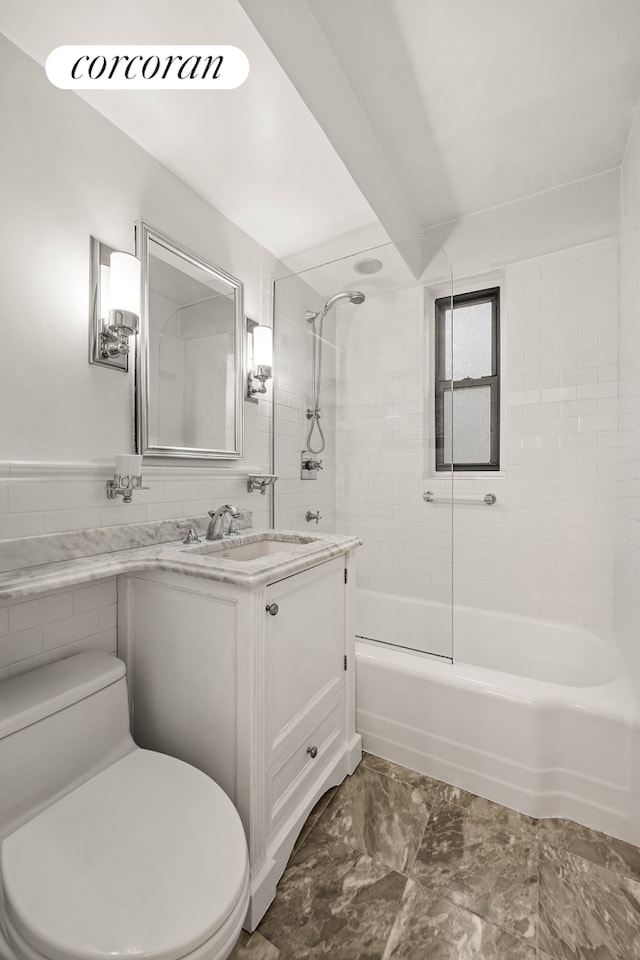 bathroom with toilet, vanity, shower / tub combination, marble finish floor, and tile walls