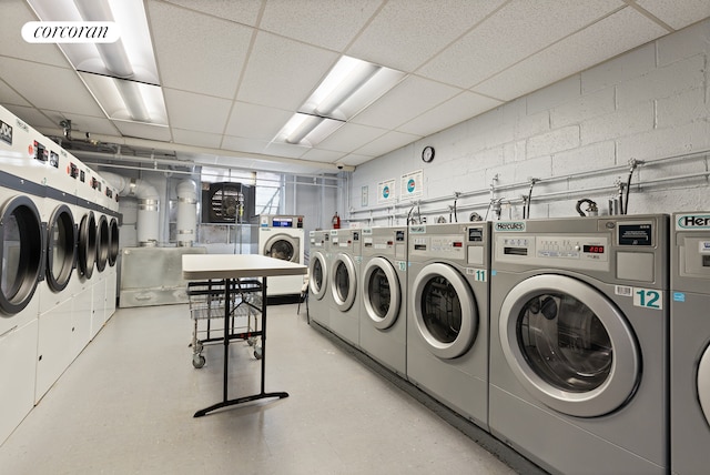 common laundry area with concrete block wall, visible vents, and washer and clothes dryer