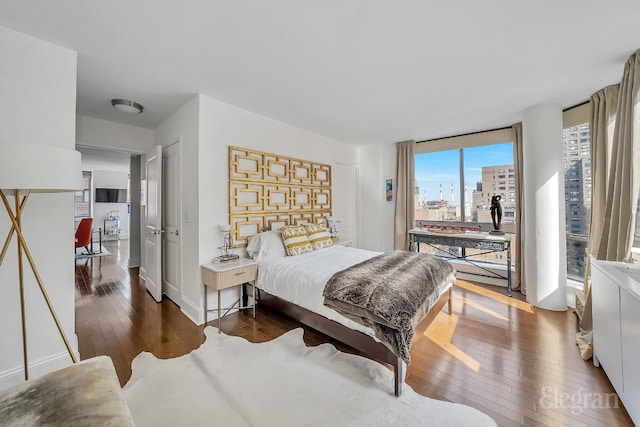 bedroom featuring dark wood-type flooring and expansive windows