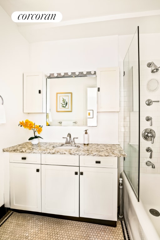 bathroom with combined bath / shower with glass door, vanity, and tile patterned flooring