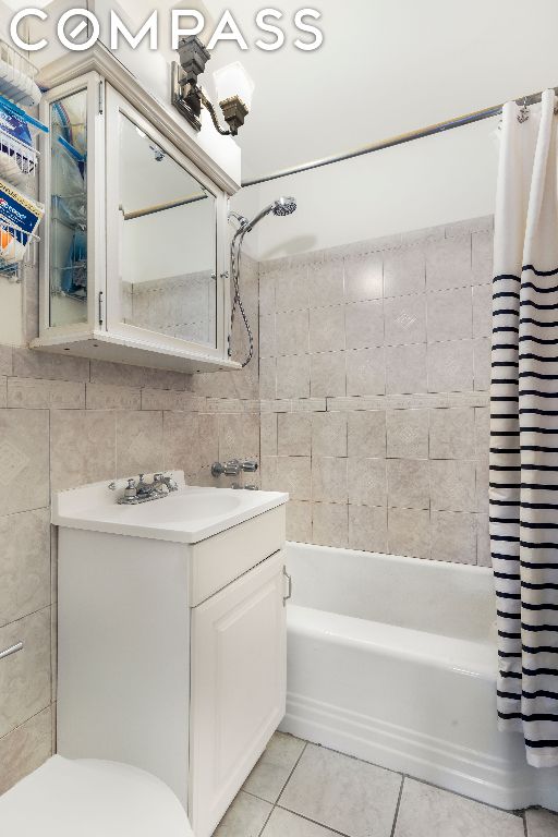 full bathroom with shower / bath combo, tasteful backsplash, tile patterned flooring, tile walls, and vanity