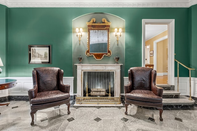 living area with a decorative wall, a wainscoted wall, ornamental molding, and a fireplace