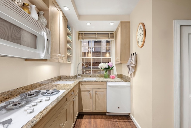 kitchen featuring white appliances, dark wood-type flooring, light brown cabinets, sink, and light stone counters