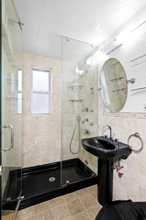 bathroom with an enclosed shower, tile patterned flooring, and tile walls