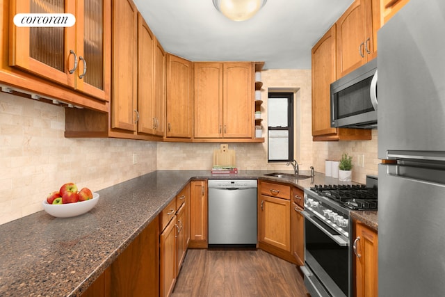 kitchen featuring appliances with stainless steel finishes, dark hardwood / wood-style flooring, dark stone counters, sink, and backsplash