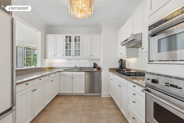 kitchen featuring crown molding, appliances with stainless steel finishes, glass insert cabinets, white cabinets, and under cabinet range hood