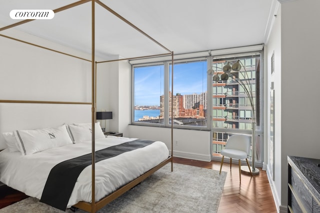 bedroom with a view of city, visible vents, baseboards, and multiple windows