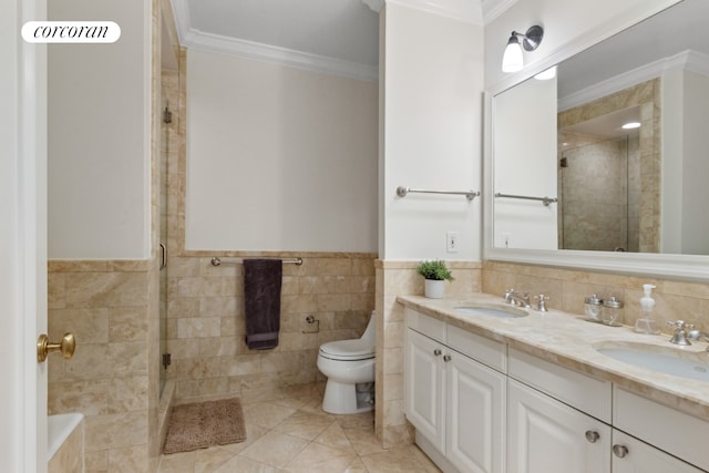 bathroom with a sink, tile walls, a shower stall, and crown molding