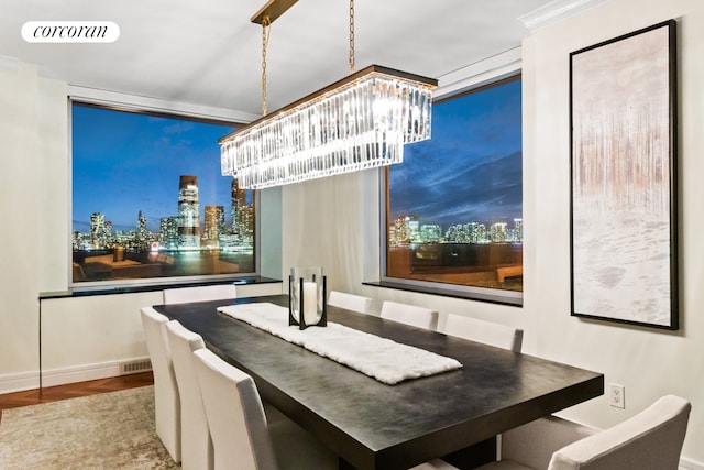 dining area with visible vents, a view of city lights, a notable chandelier, and baseboards