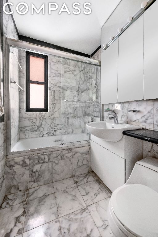 full bathroom featuring tile walls, tiled shower / bath combo, vanity, and toilet