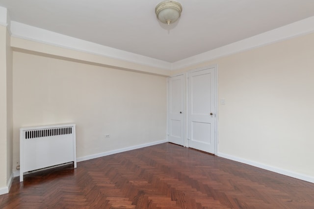 empty room featuring radiator and baseboards
