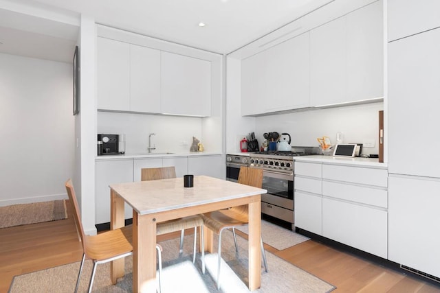 kitchen featuring light wood-type flooring, white cabinetry, stainless steel appliances, and sink