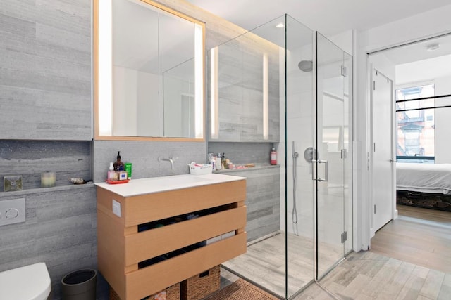 bathroom featuring vanity, tile walls, backsplash, and a shower with door