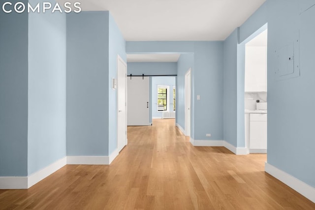 corridor featuring a barn door and light hardwood / wood-style flooring