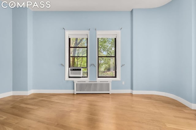 empty room with cooling unit, hardwood / wood-style floors, and radiator heating unit