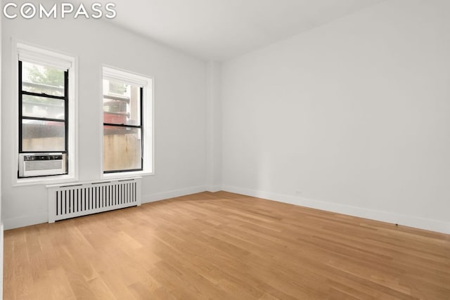 unfurnished room with radiator, light hardwood / wood-style floors, and cooling unit