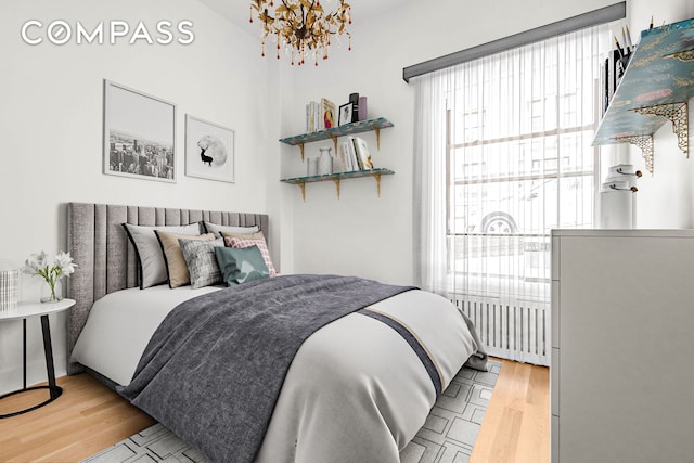 bedroom with a notable chandelier and wood finished floors