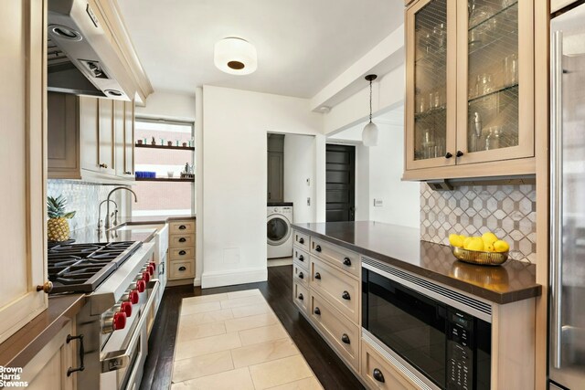 8 E 96th St Unit 14C, New York City, NY 10128 - kitchen featuring range hood, washer / clothes dryer, dark countertops, high end appliances, and a sink
