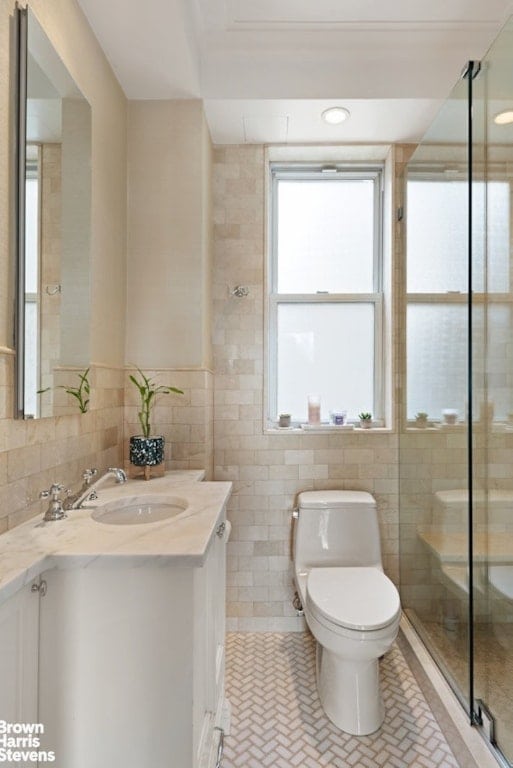 bathroom featuring plenty of natural light, tile walls, toilet, and vanity