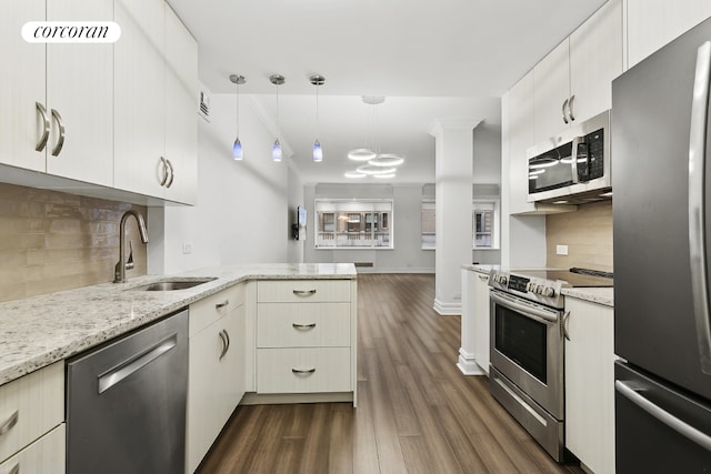 kitchen featuring decorative light fixtures, backsplash, kitchen peninsula, appliances with stainless steel finishes, and dark hardwood / wood-style flooring